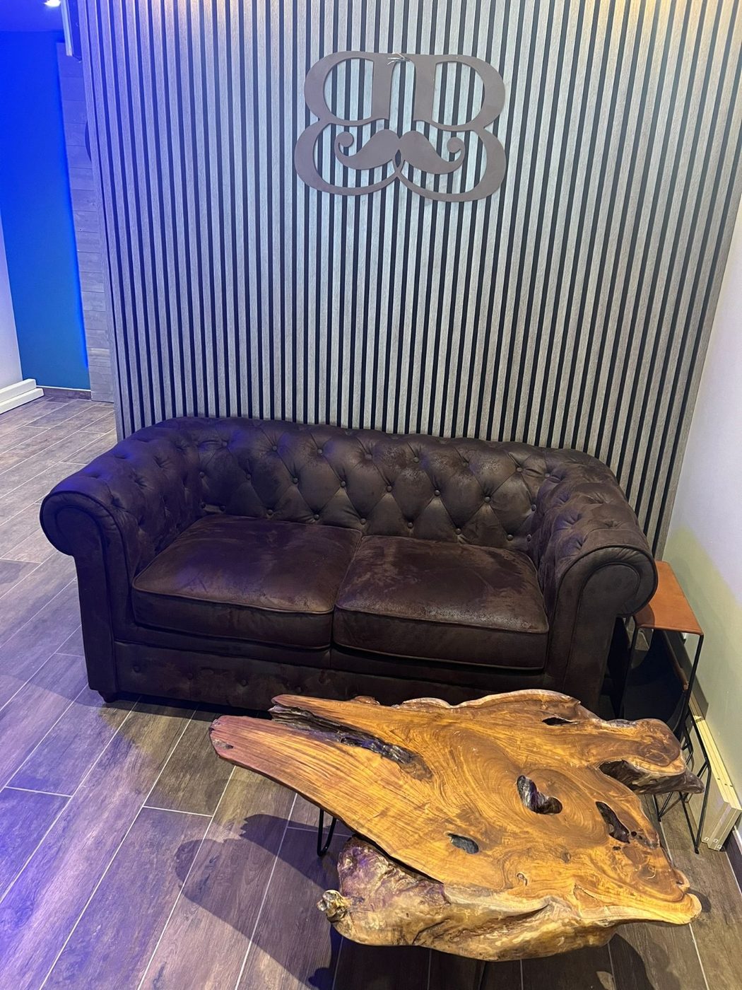 Coin détente : canapé chesterfield et logo Barbiche en bois